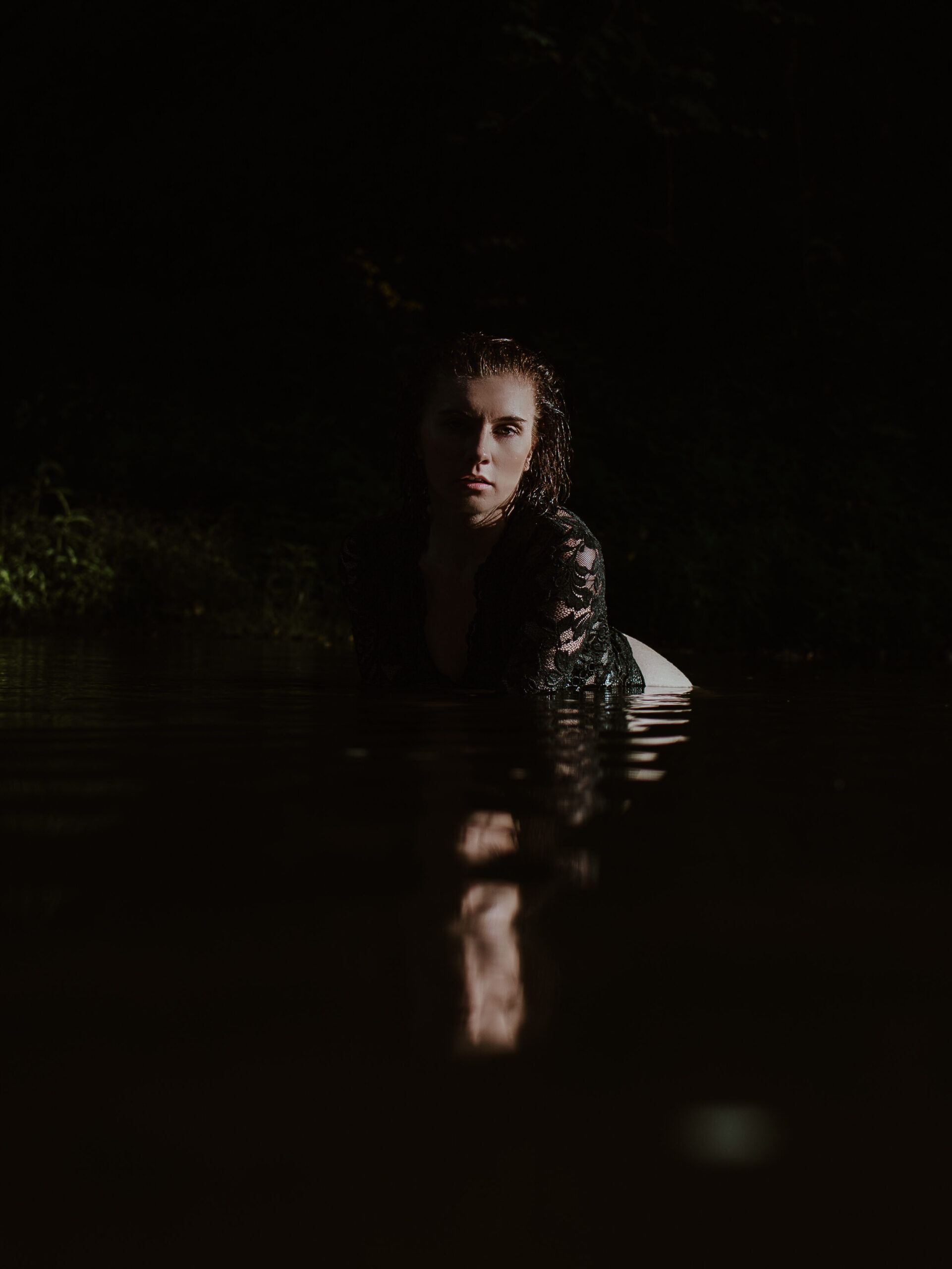 Woman in the water on hands and knees looking at the camera