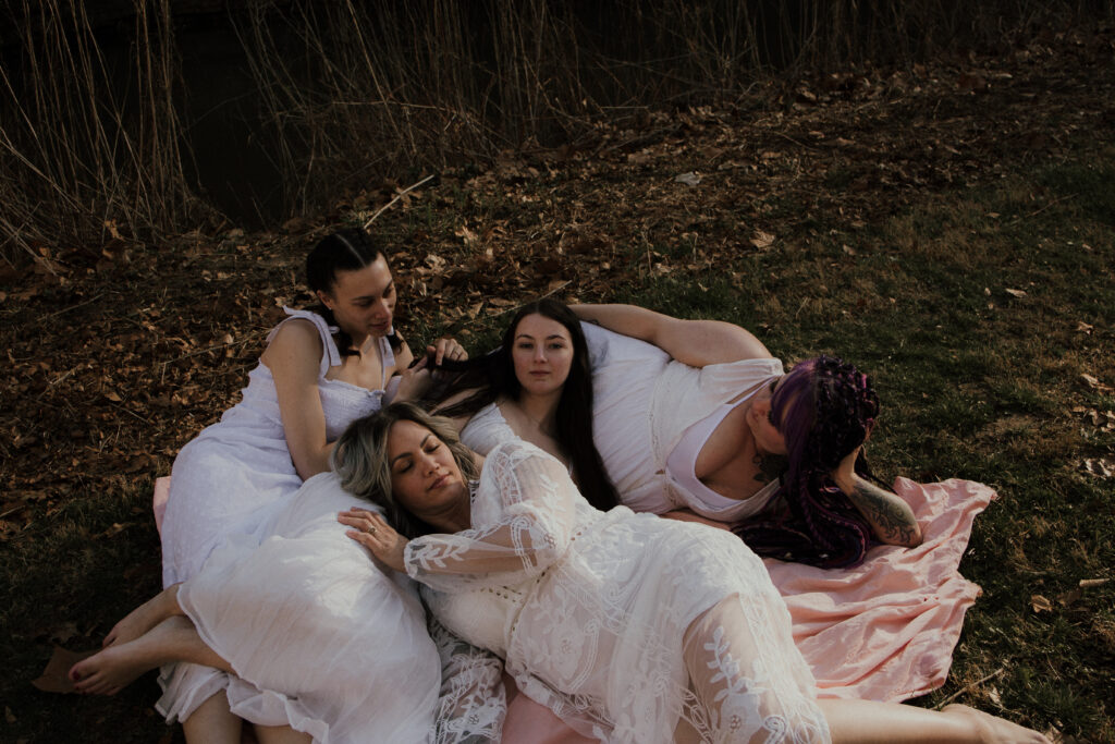 Group photo of four women laying on a blanket on the grass.